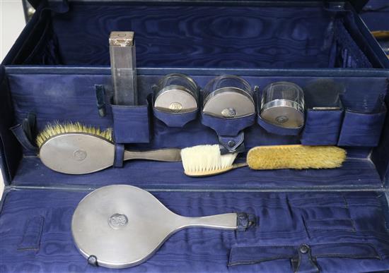 A George V travelling toilet set, with eight assorted silver mounted items and two lids, in a blue leather case.